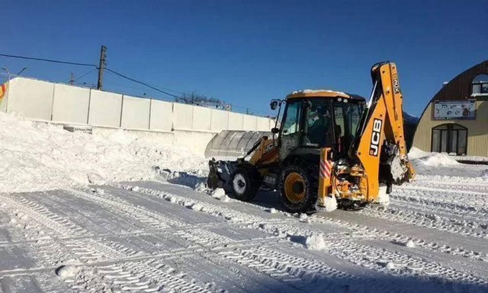 экскаватор чистит площадку от снега